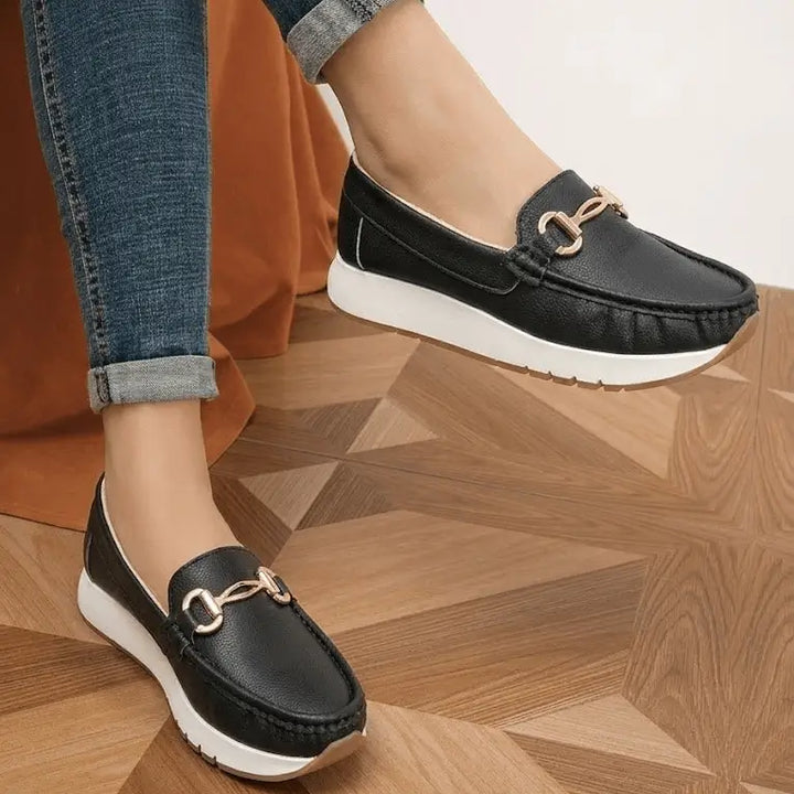 Mocasín Bolichero Maíra negro slip-on para mujer, detalle metálico dorado y suela blanca antideslizante, plantilla acolchada para máximo confort diario y estilo casual elegante