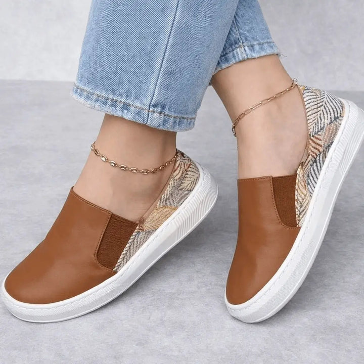 Bolichero Nayara tenis slip on mujer en color marrón con detalles estampados de inspiración étnica, suela antideslizante y plantilla acolchonada para caminar con máximo confort y estilo casual.