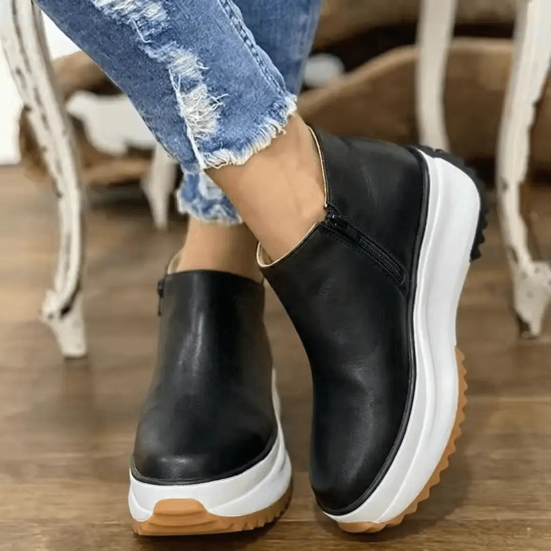 Botín Luxe para mujer negro con suela gruesa blanca y base de goma antideslizante, corte bajo con cierre lateral, forro acolchado y plantilla ergonómica que brinda comodidad todo el día y estilo casual urbano.