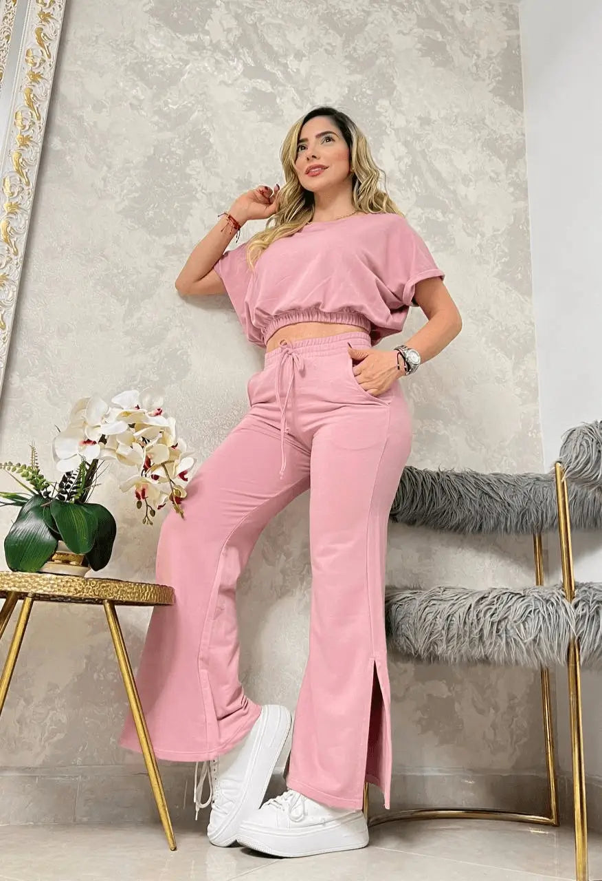 Outfit completo con conjunto bota campana para mujer en rosa pastel, top cropped de manga corta con cintura elástica y pantalón acampanado con abertura lateral, combinado con tenis blancos, cómodo y versátil para looks urbanos y uso diario