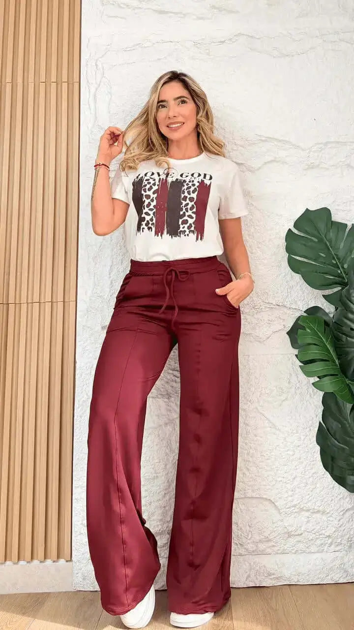 Mujer posa con conjunto compuesto por camiseta blanca manga corta de algodón y pantalón palazzo burdeos de satén con cintura ajustable, look versátil y cómodo ideal para uso diario, oficina y salidas urbanas