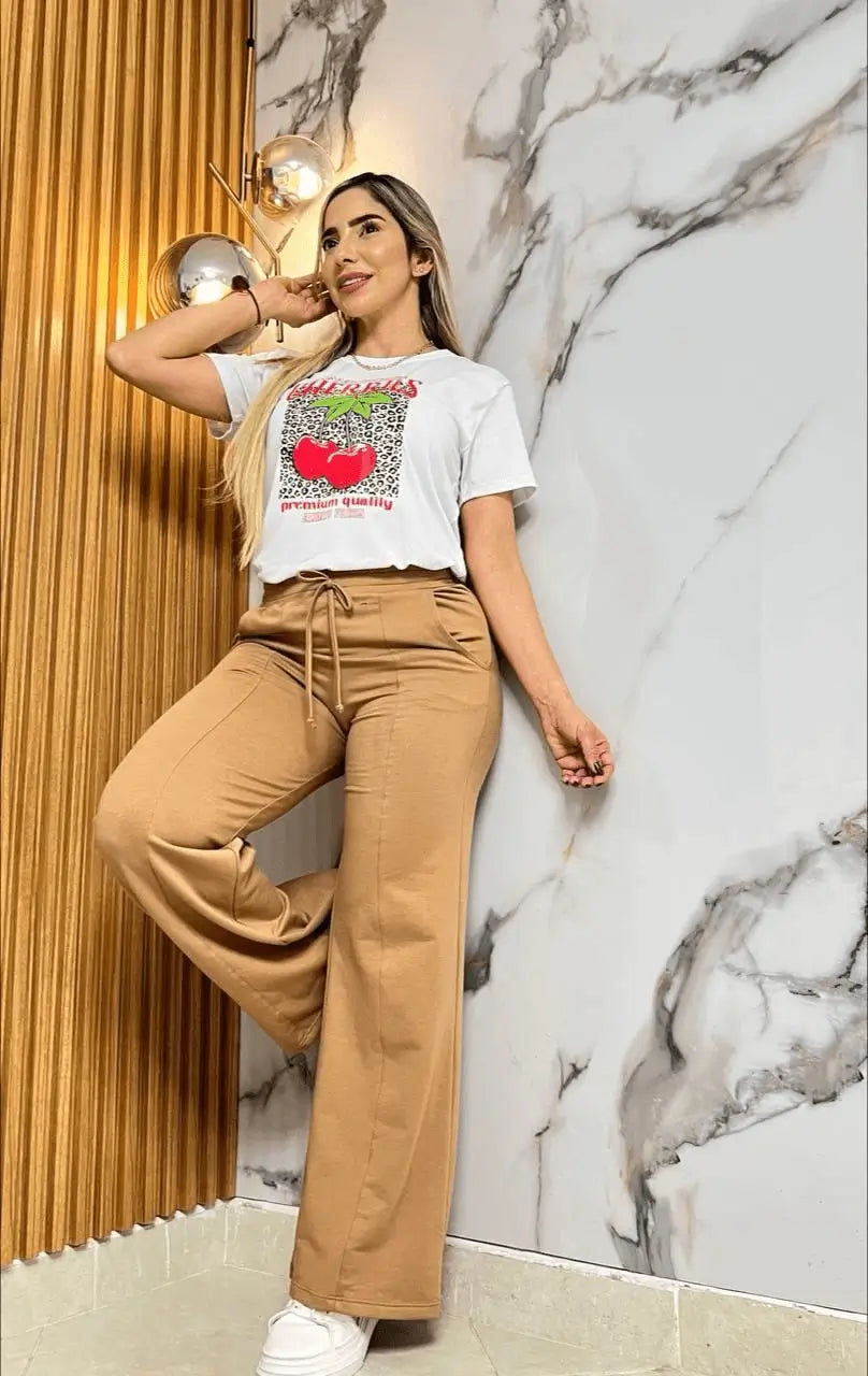 Conjunto bota campana Cereza con top blanco de algodón estampado de cerezas y pantalón bootcut color caramelo, combinado con zapatillas blancas de plataforma para un look casual chic, cómodo y versátil que estiliza la figura