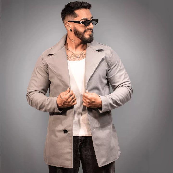 Abrigo o sobretodo para hombre en un tono gris claro sofisticado, perfecto para combinar con un look urbano. El modelo lleva gafas de sol y camisilla blanca. Compra online segura con envío nacional en Colombia
