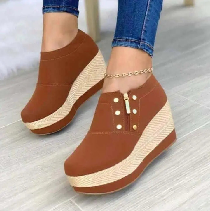 Tacones Olivia color marrón con plataforma alta, diseño cómodo y moderno con cierre lateral para fácil ajuste, ideales para uso diario que ofrecen estilo y soporte para los pies, combinan con jeans ajustados para un look casual y elegante en cualquier ocasión.
