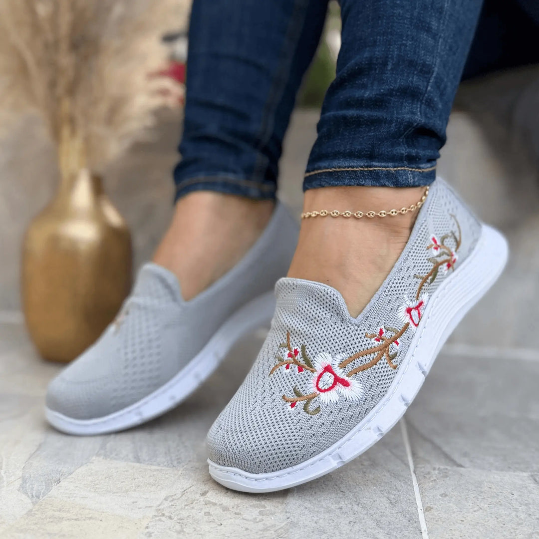 Zapatillas Florenza grises con bordado floral en tejido knit transpirable, suela liviana antideslizante y plantilla acolchonada que ofrece amortiguación y confort ergonómico diario