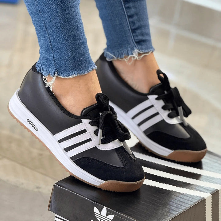 Zapatillas Marbella estilo retro en negro y blanco con suela de goma antideslizante, empeine de material sintético y gamuza, cordones reforzados y plantilla acolchada para máximo confort en caminatas y actividades urbanas.