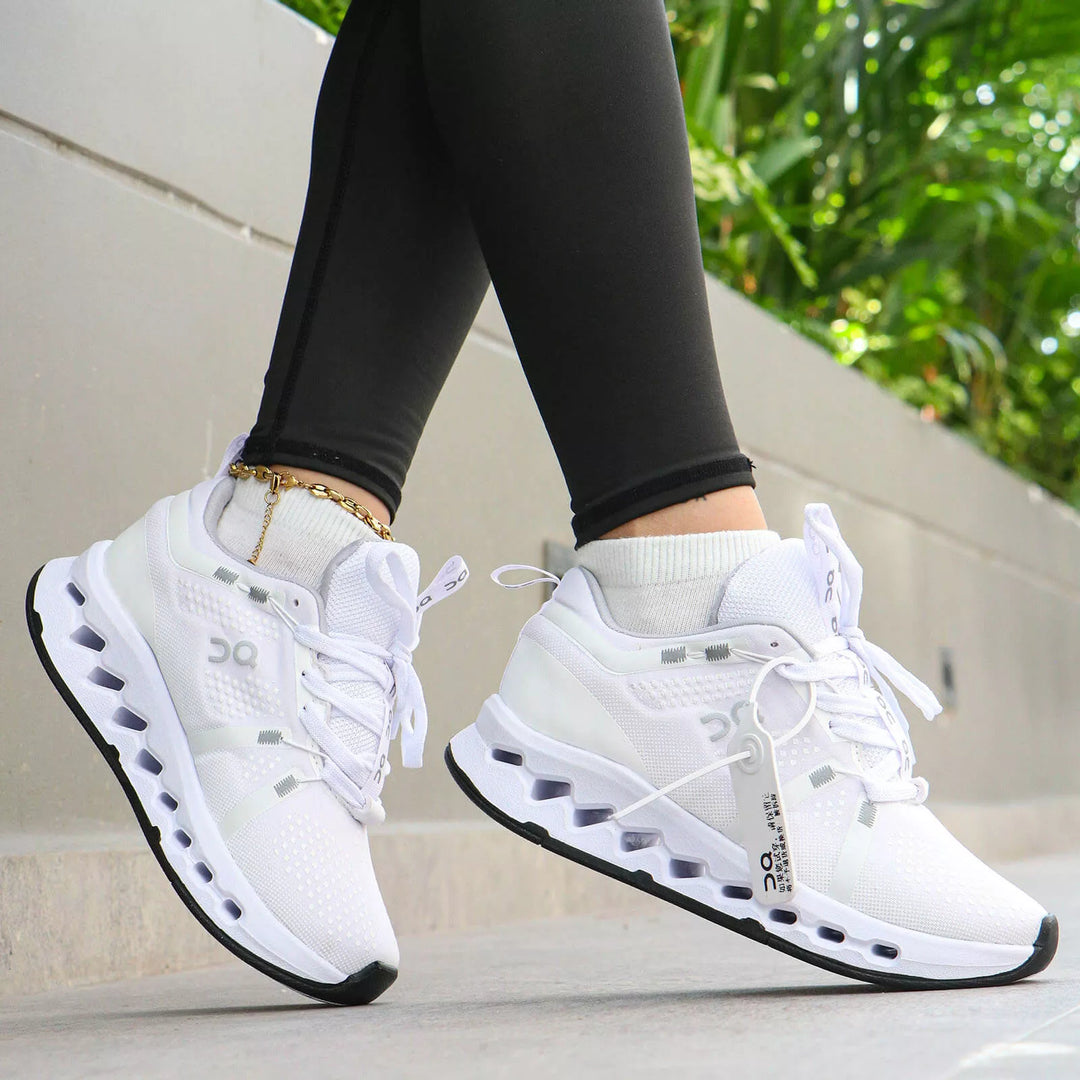 Outfit deportivo de dama con licras negras, medias cortas y tenis marca On totalmente blancos en tendencia. Una toma detallada que resalta un look casual, cómodo y premium para entrenar o el diario.