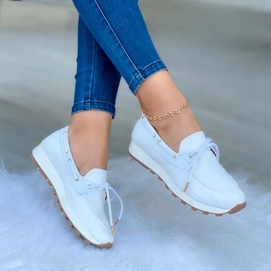 Zapatos femeninos blancos estilo náutico con suela antiderrapante y diseño cómodo, ideales para uso diario y caminatas prolongadas, combinados con jeans ajustados, perfectos para un look casual y moderno.