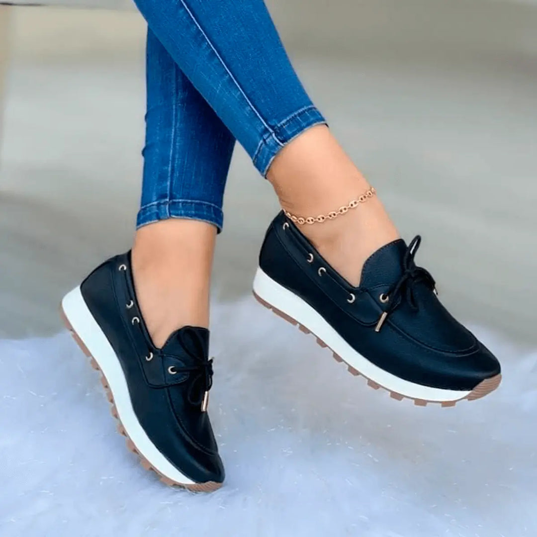 Zapatos cómodos y modernos para mujer en color negro con suela antiderrapante blanca, diseño casual ideal para uso diario, combinación perfecta con jeans, material resistente y acabado elegante que ofrece soporte y confort durante todo el día.