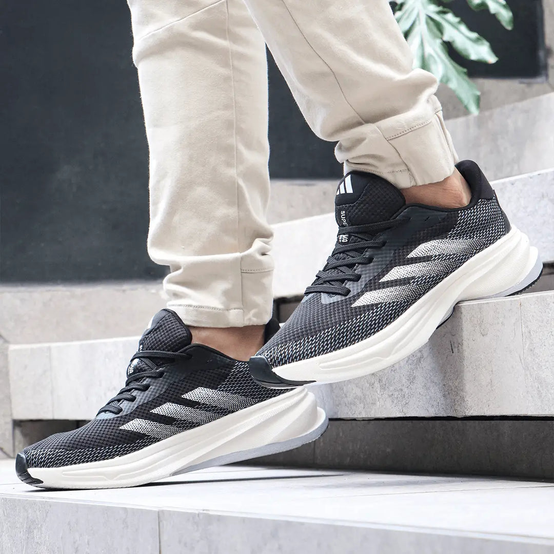 zapatillas deportivas negras con detalles en blanco, turquesa y rosa, diseño ligero y transpirable, suela gruesa para máxima amortiguación y comodidad para correr y caminar, calzado ideal para entrenamiento y uso diario